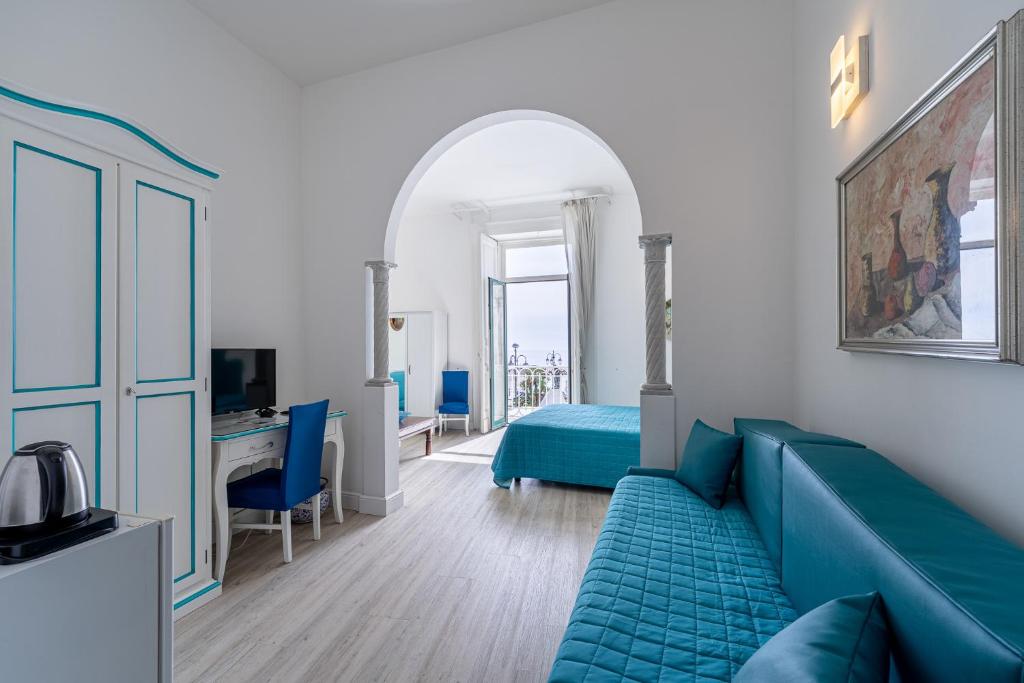 a living room with a blue couch and a bed at Hotel Fontana in Amalfi