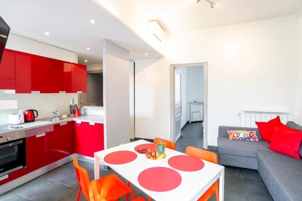 - une cuisine et un salon avec des armoires rouges et une table dans l'établissement Bright and modern 2 BR in the heart of Antibes!, à Antibes