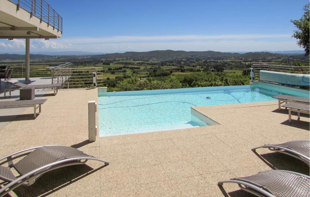 - une piscine avec des chaises et une vue sur les montagnes dans l'établissement Cozy Home In Rochefort-Du-Gard, à Rochefort-du-Gard