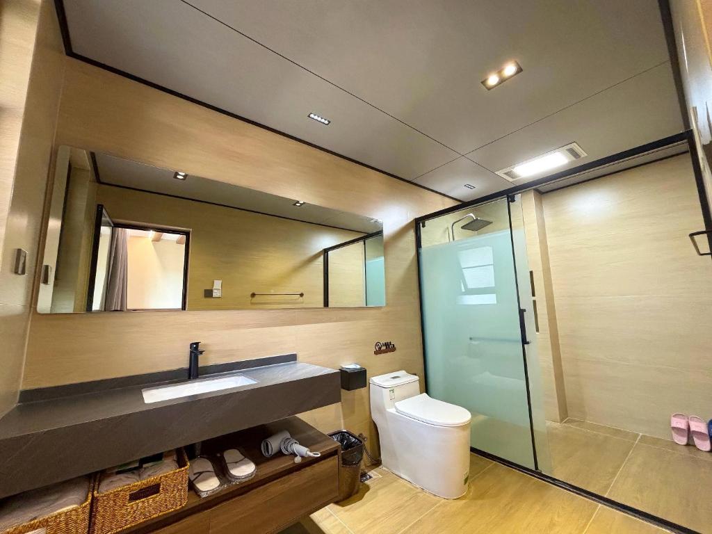 Un baño con inodoro, lavabo y espejo. en Luyu Shijian B&B, en Lijiang
