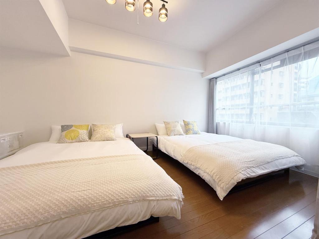 two beds in a white room with a window at The Inui N3 in Tokyo