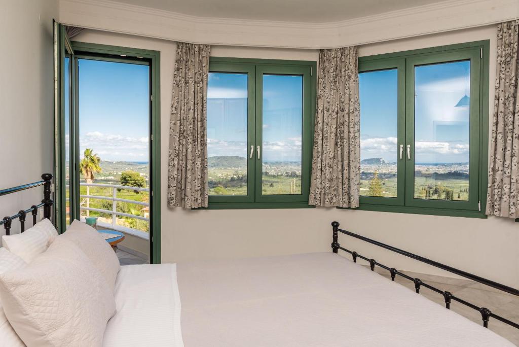 Agia MarinaにあるFagias Luxury Apartmentのベッドと大きな窓のある寝室