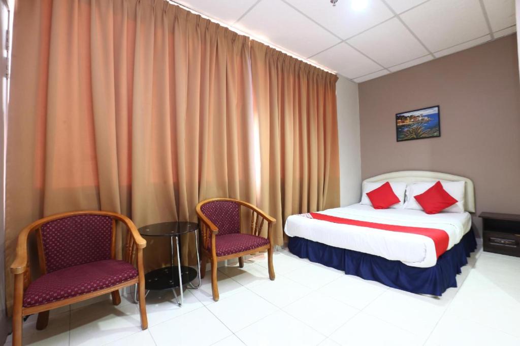 a hotel room with a bed and two chairs at Hotel O Destiny Riverside Hotel in Kota Bharu