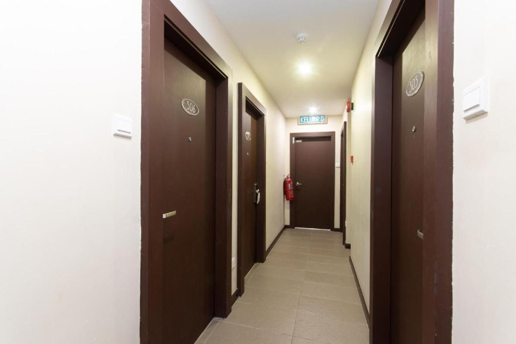 a hallway with brown doors and a tile floor at Capital O 89344 Labuan Avenue Hotel in Labuan