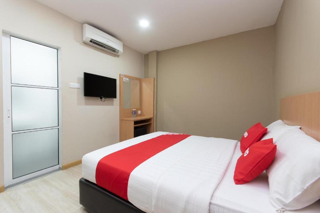 a bedroom with a large bed with red pillows at Capital O 89344 Labuan Avenue Hotel in Labuan
