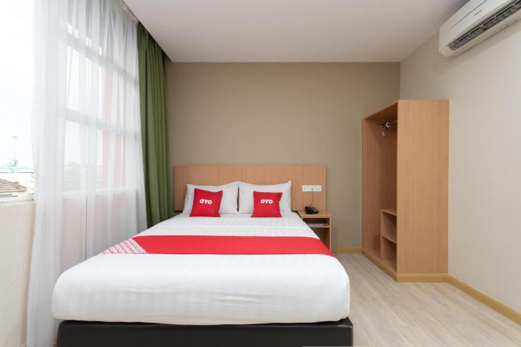 a bedroom with a large bed with red pillows at Capital O 89344 Labuan Avenue Hotel in Labuan