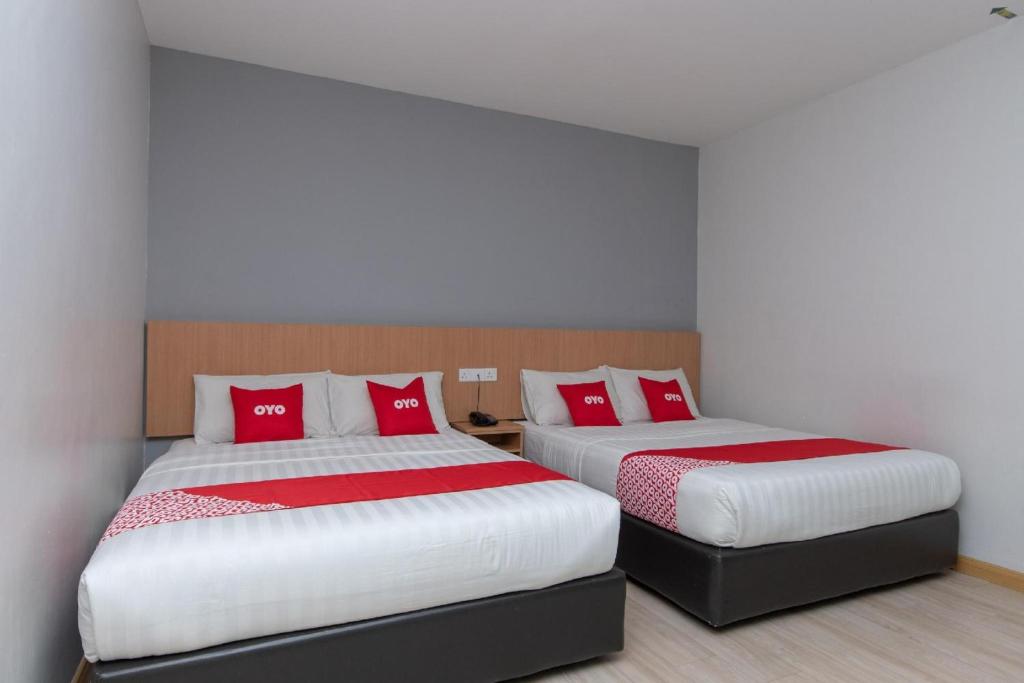 two beds in a room with red pillows at Capital O 89344 Labuan Avenue Hotel in Labuan