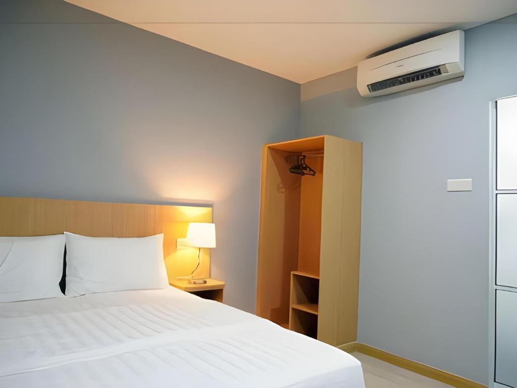 a bedroom with a white bed and a lamp at Capital O 89344 Labuan Avenue Hotel in Labuan