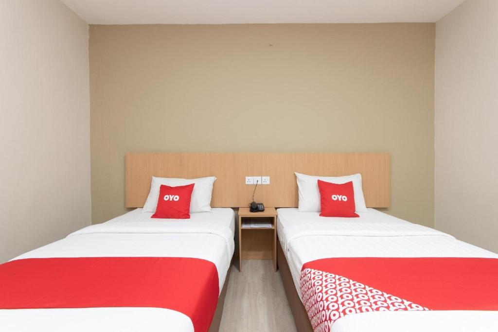 two beds with red pillows in a room at Capital O 89344 Labuan Avenue Hotel in Labuan