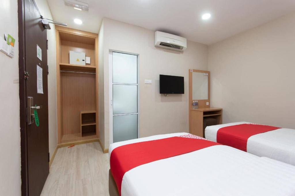 a hotel room with two beds and a television at Capital O 89344 Labuan Avenue Hotel in Labuan