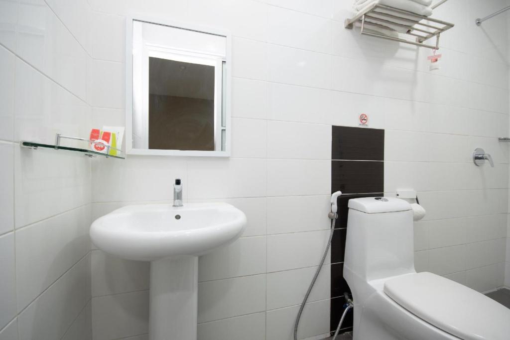 a white bathroom with a sink and a toilet at Capital O 89344 Labuan Avenue Hotel in Labuan