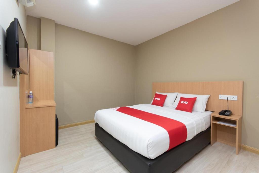 a bedroom with a bed with red pillows and a tv at Capital O 89344 Labuan Avenue Hotel in Labuan