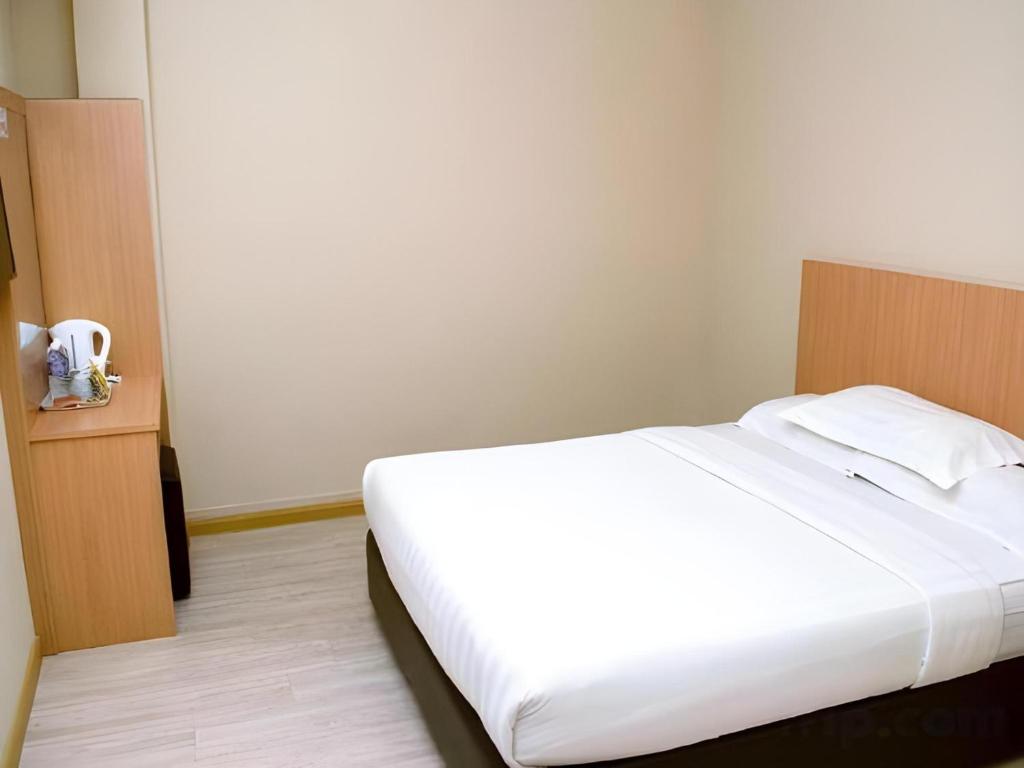 a bedroom with a large white bed and a white wall at Capital O 89344 Labuan Avenue Hotel in Labuan