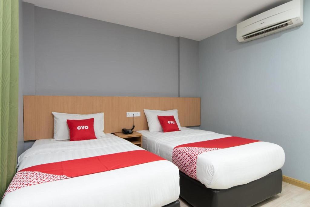 two beds with red pillows in a room at Capital O 89344 Labuan Avenue Hotel in Labuan