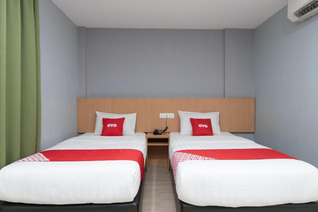 two beds with red pillows in a room at Capital O 89344 Labuan Avenue Hotel in Labuan