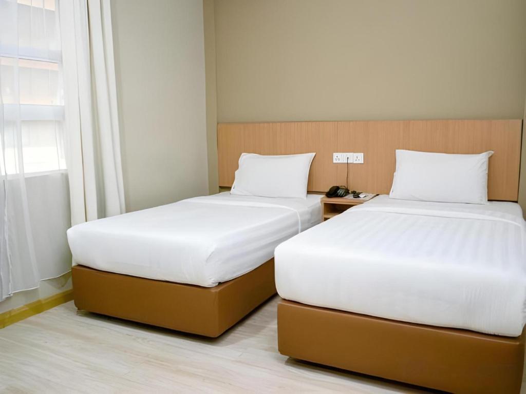 two beds sitting next to each other in a room at Capital O 89344 Labuan Avenue Hotel in Labuan