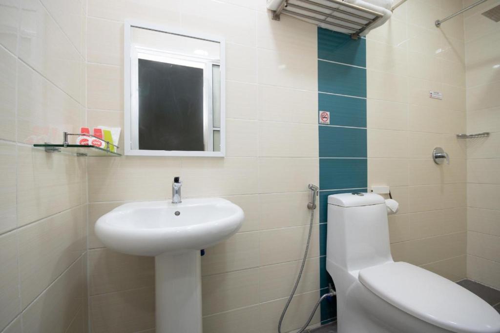 a bathroom with a sink and a toilet and a mirror at Capital O 89344 Labuan Avenue Hotel in Labuan