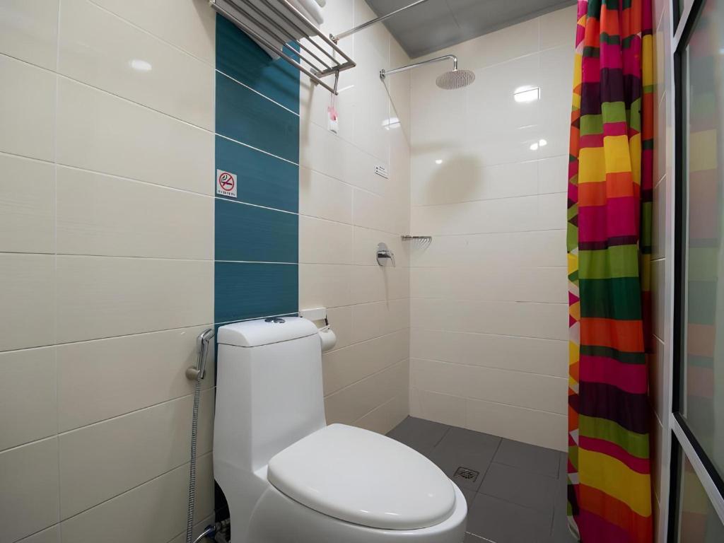 a bathroom with a toilet and a colorful shower curtain at Capital O 89344 Labuan Avenue Hotel in Labuan