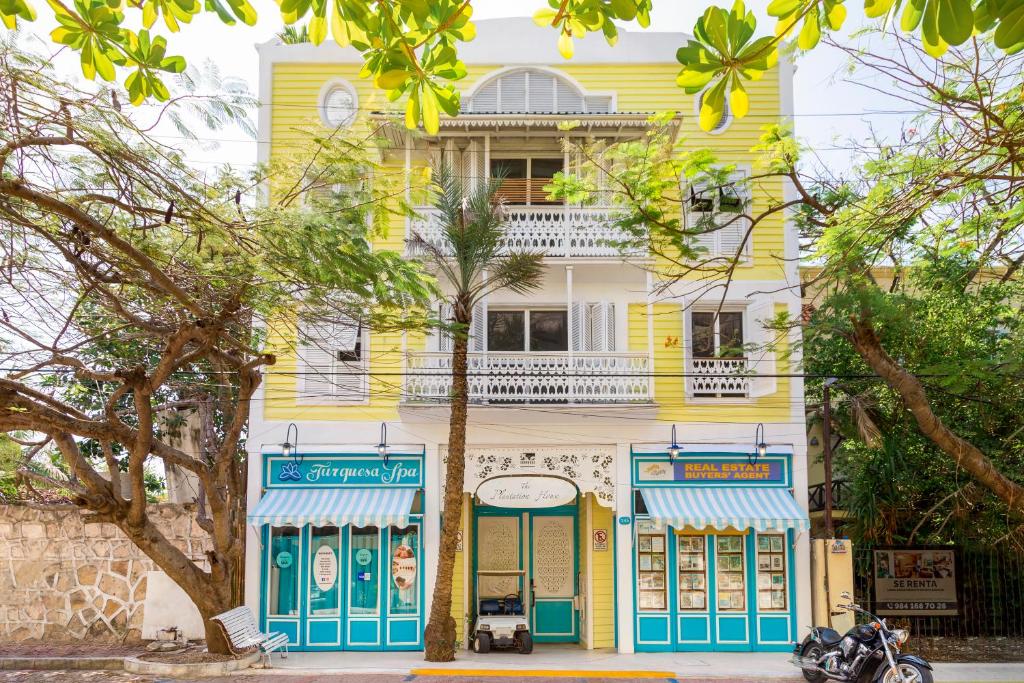 a yellow and blue building with a tree in front of it at Plantation House Trinidad suite in Playa del Carmen