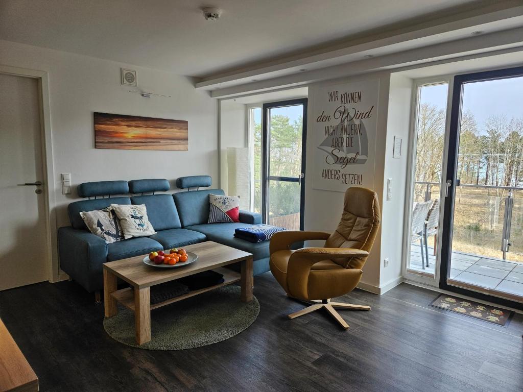 a living room with a blue couch and a chair at Ankerplatz am Südstrand, Fewo mit 2 Schlafzimmer und eigenen Strandkorb in Binz