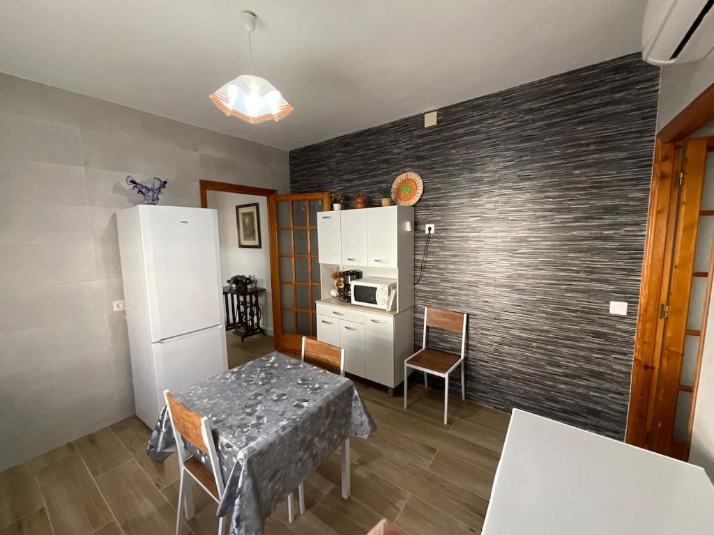 a kitchen with a table and a white refrigerator at Casa rural VTAR con piscina in Rosal de la Frontera