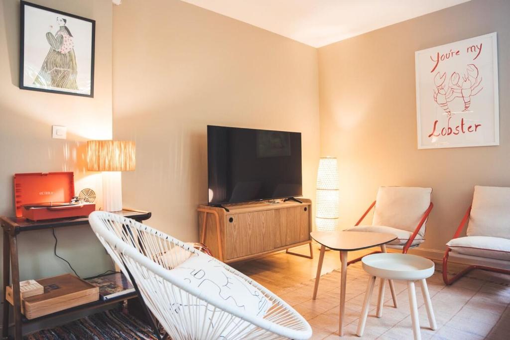 un salon avec une télévision, un canapé et des chaises dans l'établissement Grand appartement rénové, tout confort, à Nancy
