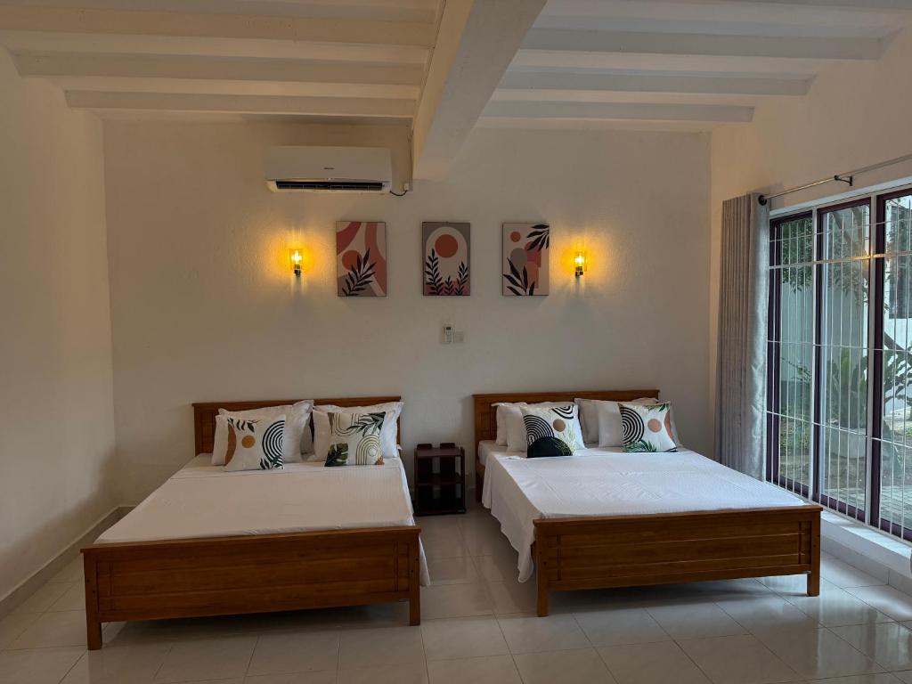 a bedroom with two beds and a large window at Dwellio -Ratmalana - Greater Colombo in Ratmalana