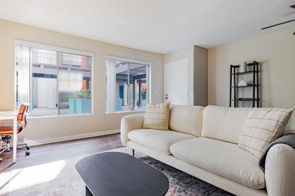 a living room with a couch and two windows at Blueground Glendale pool AC nr Americana LAX-1319 in Glendale