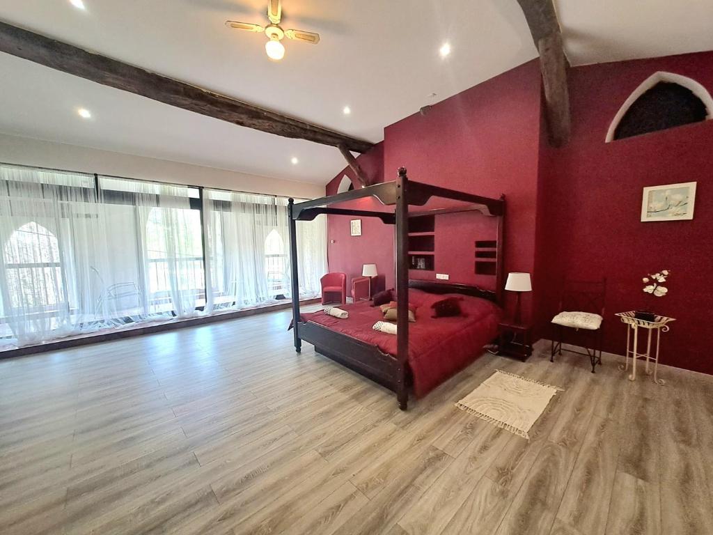 a bedroom with a canopy bed in a red wall at Les chambres d'hôtes du Moulin in Arles-sur-Tech