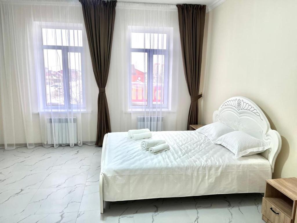 a bedroom with a white bed and two windows at New hotel BEKARYS in Astana