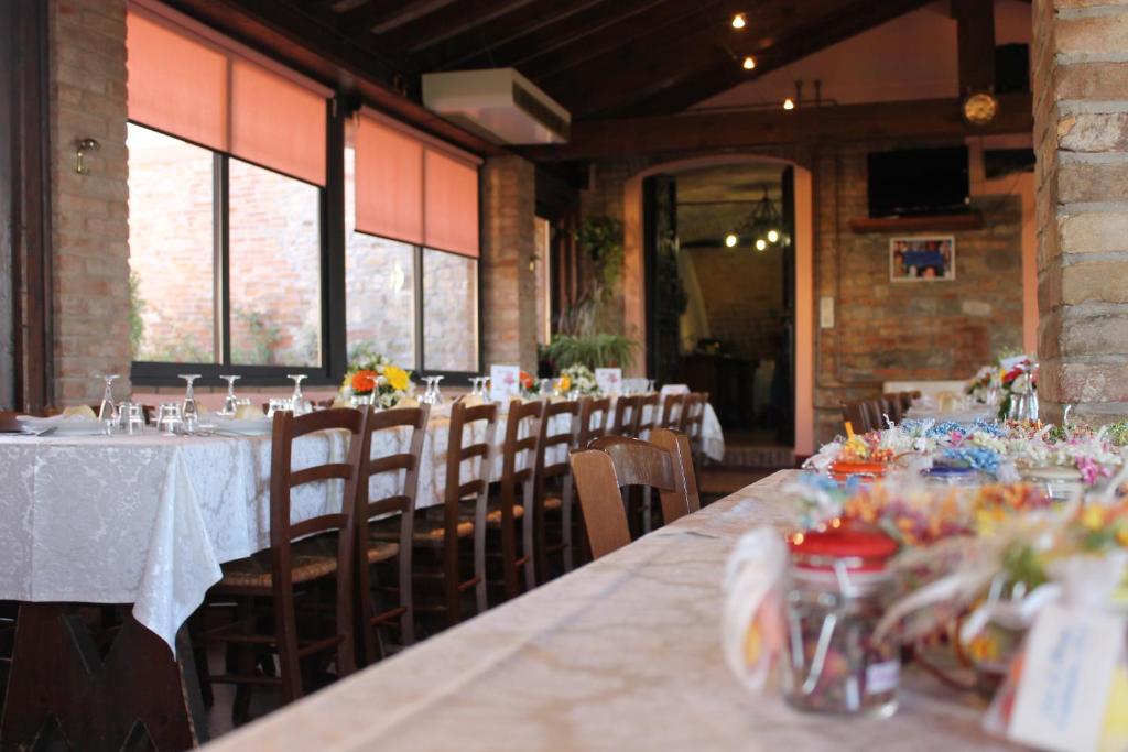 a dining room with long tables and chairs and windows at Agriturismo Le Casette in Castelvetro di Modena