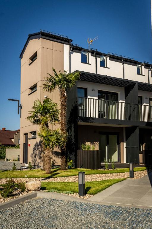 a building with palm trees in front of it at Apartamenty Wyspa Jastarnia Morski in Jastarnia
