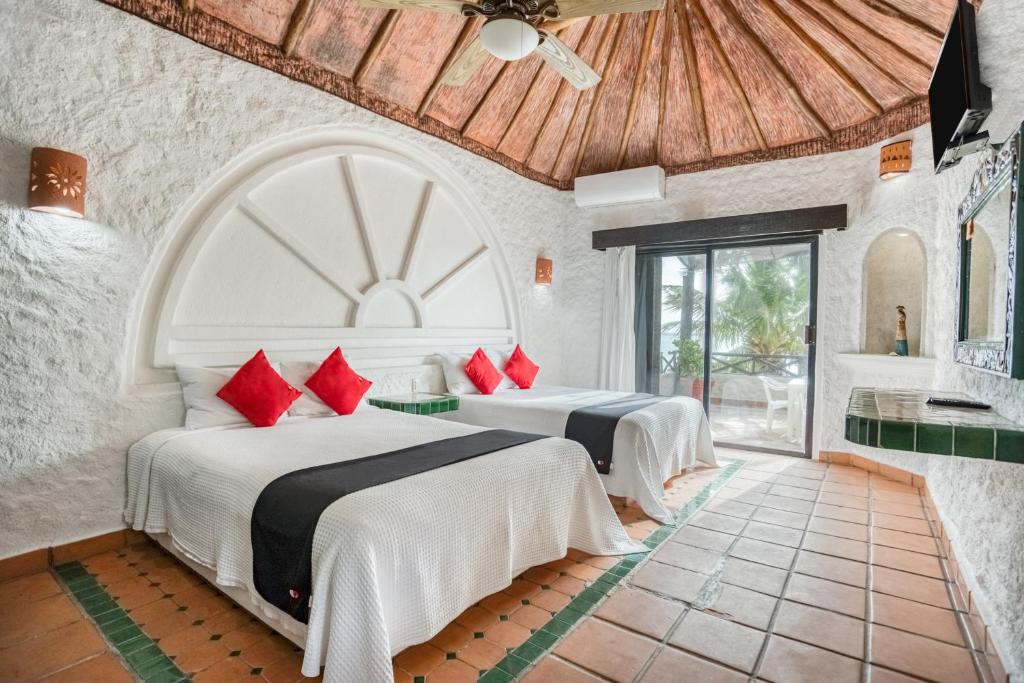 two beds in a room with a bathroom at Capital O Mimi Del Mar, Playa del Carmen in Playa del Carmen