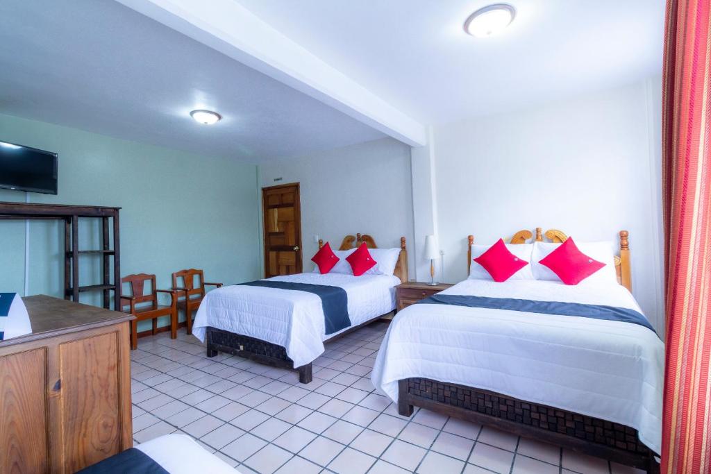 a hotel room with two beds and a television at Capital O Hospedaje Los Angeles San Cristobal De Las Casas in San Cristóbal de Las Casas