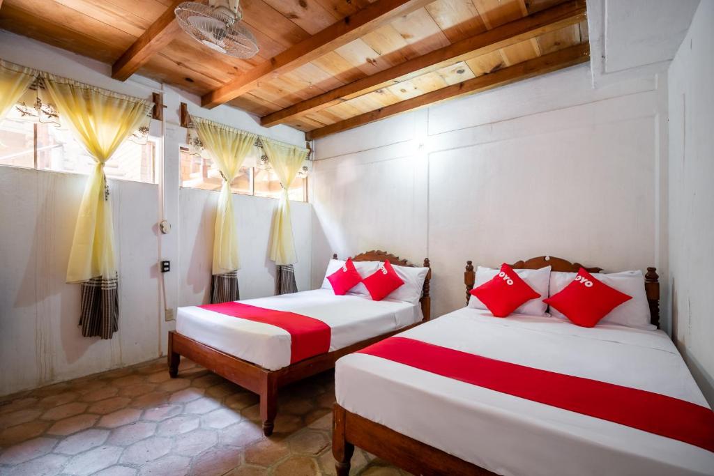 two beds in a room with red and white pillows at OYO Cabañas Abril, Mazunte in Mazunte