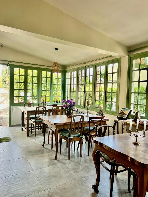 a dining room with tables and chairs and windows at Hotel Le Ponteil in Antibes