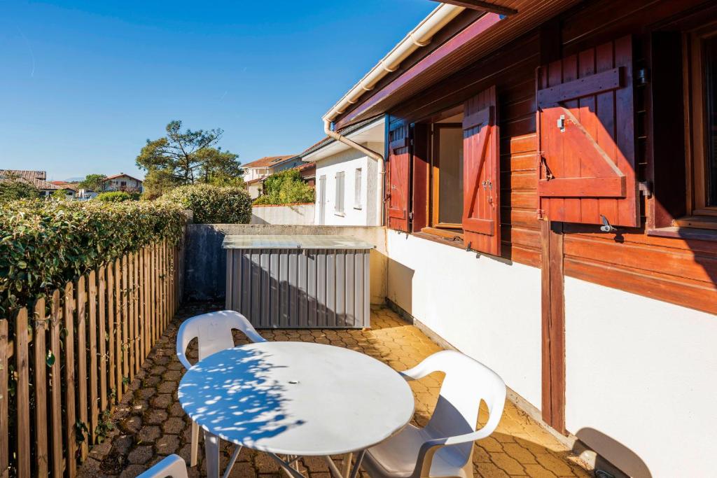 un patio avec une table et des chaises sur un balcon dans l'établissement Chardons bleus - villa 6p, à Capbreton