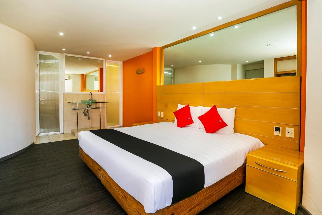 a bedroom with a large bed with red pillows at Capital O Hotel Casa Blanca, Morelia in Morelia