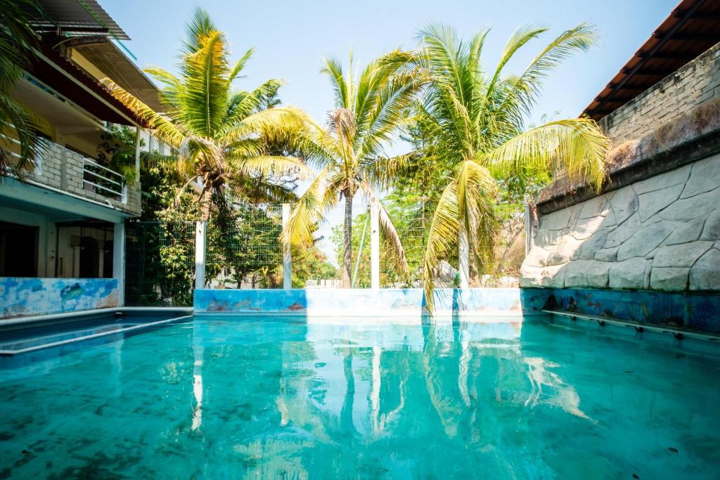 a swimming pool with palm trees in front of a house at OYO Hotel Betsua Vista Hermosa, Huatulco in Santa Cruz Huatulco