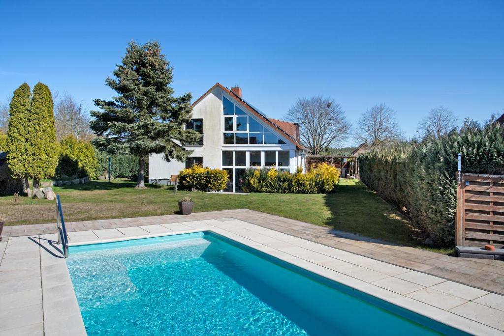 a swimming pool in front of a house at Ferienwohnung Waldidyll in Wolgast