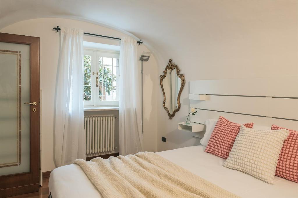 a bedroom with a white bed with pillows and a window at Il nido di Cate in Fossano