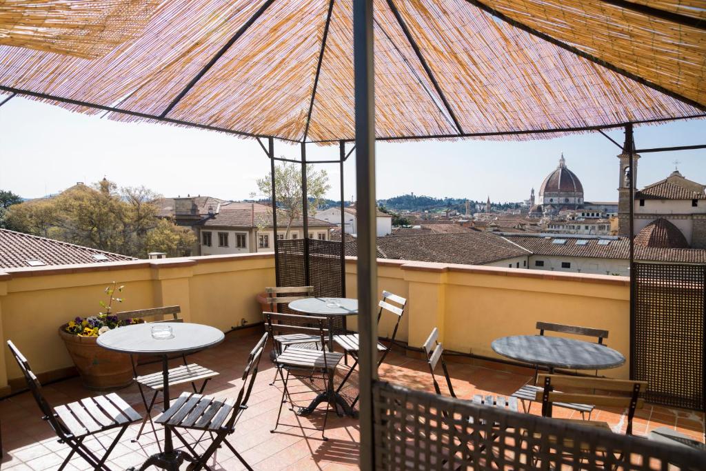 balcón con mesas, sillas y sombrilla en Hotel Panorama en Florence