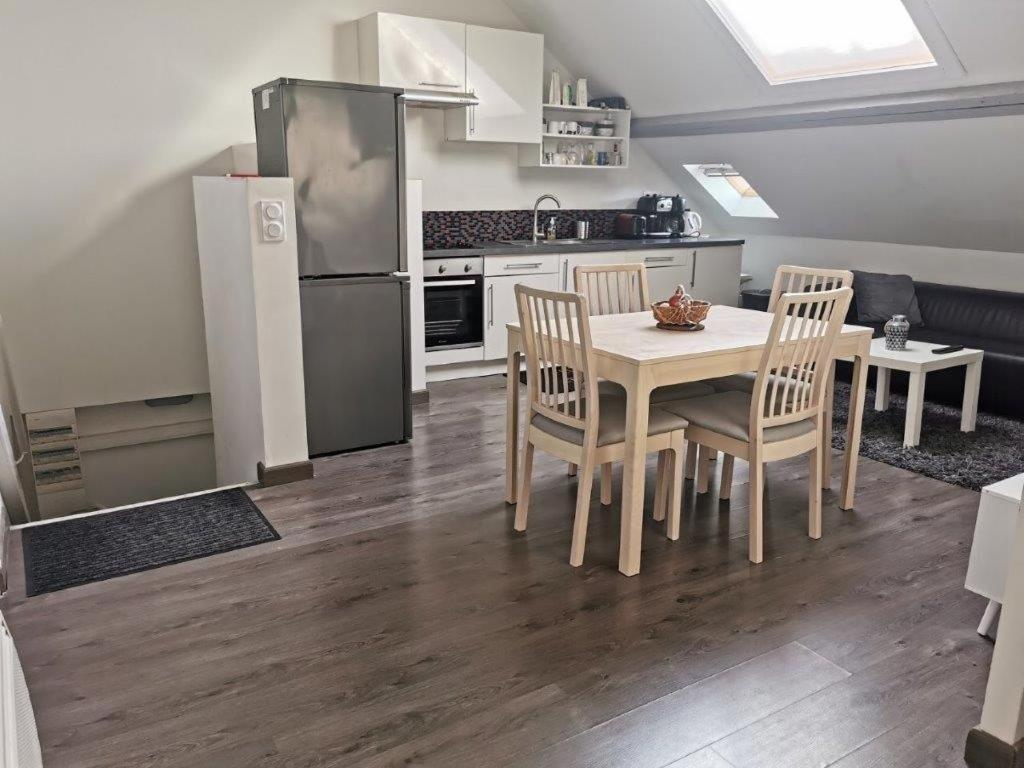 une cuisine avec une table, des chaises et un réfrigérateur dans l'établissement Suite Condorcet 3 Ch 3 Sdb, à Reims