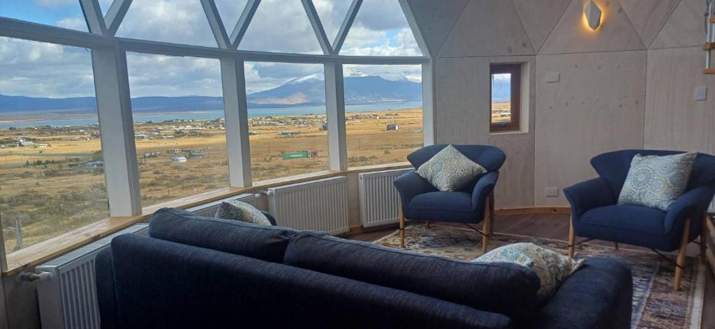 a living room with a couch and two chairs and a large window at Dome with Epic Fjord Views in Puerto Natales