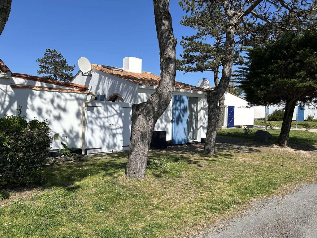 une maison blanche avec un arbre devant dans l'établissement Maison 2 pièces, 4 pers, Piscine, Parking, Bretignolles-sur-Mer - FR-1-224A-75, à Bretignolles-sur-Mer