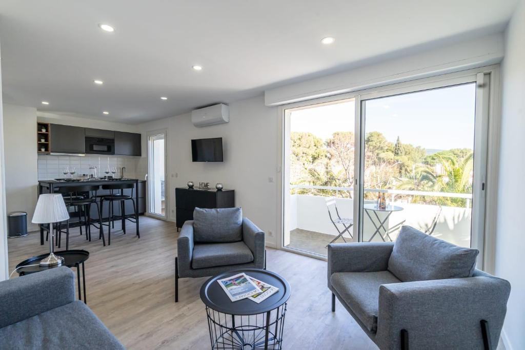 un salon avec un canapé et des chaises et une cuisine dans l'établissement La Ciotat T2 Climatisé Plage Lumière avec garage, à La Ciotat