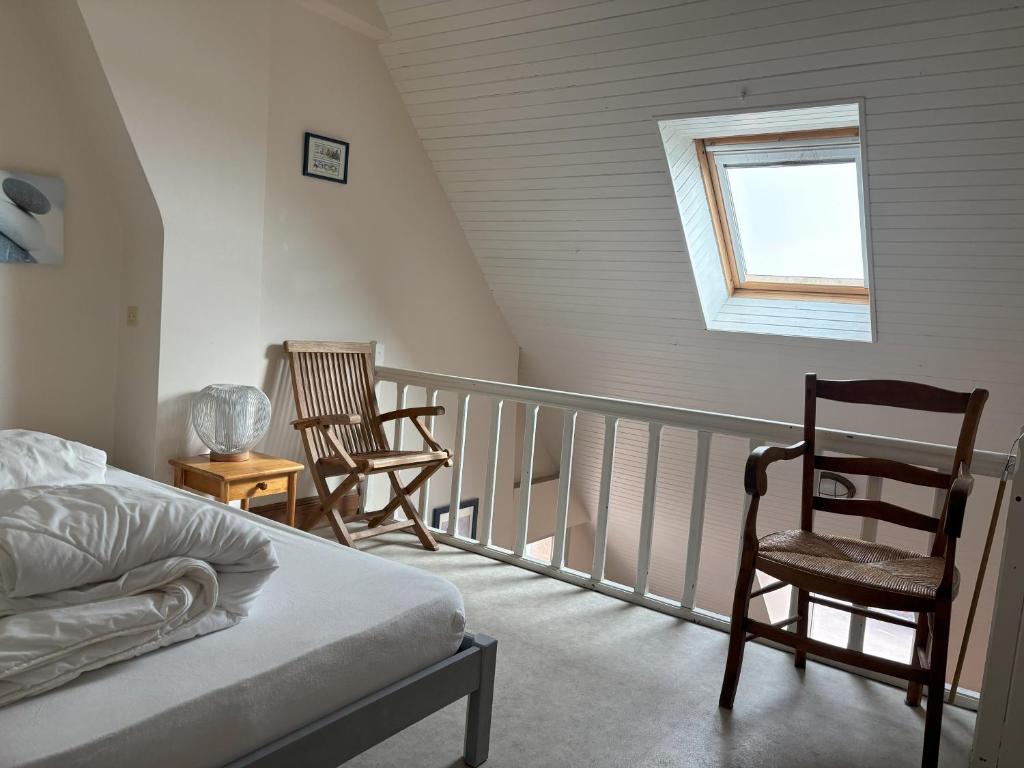 a bedroom with a balcony with two chairs and a bed at Studio les Mouettes in Perros-Guirec