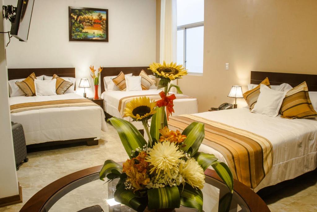 a hotel room with two beds and a table with flowers at Hotel Europa in Iquitos