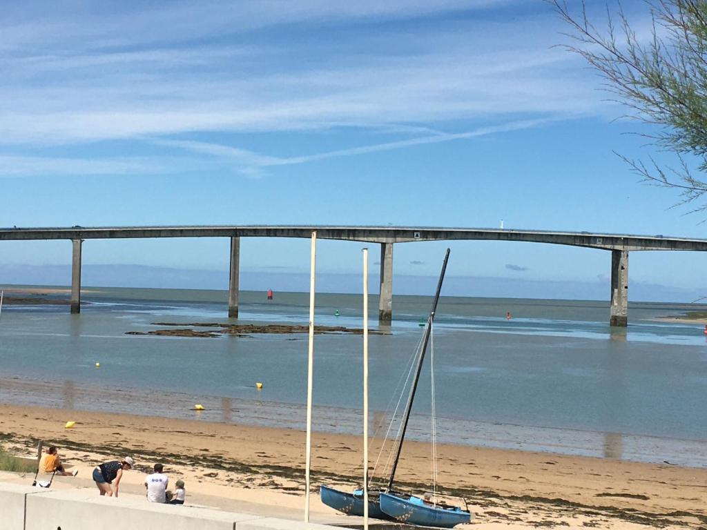 un bateau sur la plage avec un pont en arrière-plan dans l'établissement maison laréral mer fromentine, à La Barre-de-Monts