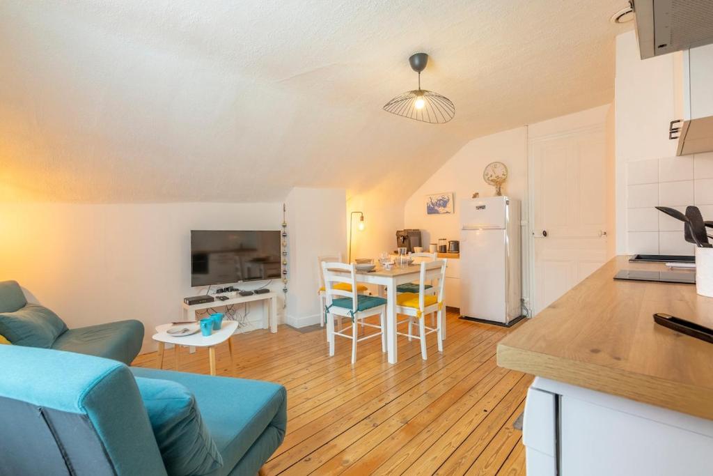 eine Küche und ein Wohnzimmer mit einem Tisch und einem Kühlschrank in der Unterkunft Au cœur de la ville, traversant et tout confort in Vannes